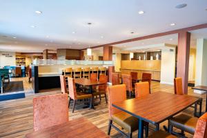 米尔堡TownePlace Suites by Marriott Fort Mill at Carowinds Blvd的一间带木桌椅的餐厅和一间酒吧