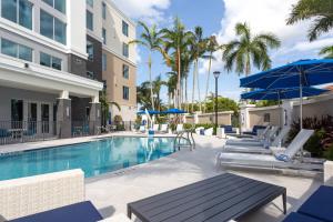 棕榈滩花园Residence Inn Palm Beach Gardens的一个带椅子和遮阳伞的游泳池
