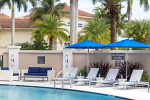 棕榈滩花园Residence Inn Palm Beach Gardens的酒店旁的游泳池配有椅子和遮阳伞