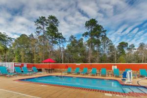 萨拉兰TownePlace Suites by Marriott Mobile Saraland的一个带蓝色躺椅和红色墙壁的游泳池
