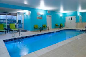 东兰辛SpringHill Suites by Marriott East Lansing University Area, Lansing Area的一个带绿色桌椅的游泳池