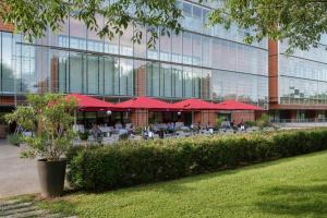 里昂里昂塞特万豪国际酒店的大楼前的一间餐厅,配有红色遮阳伞