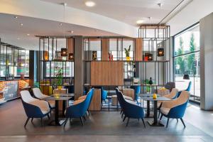 苏黎世北苏黎世万怡酒店的餐厅设有蓝色的椅子和桌子以及窗户。