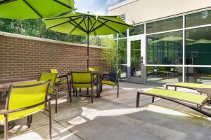 埃佩克斯SpringHill Suites by Marriott Raleigh Apex的一个带桌椅和绿色遮阳伞的庭院
