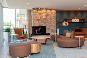 卡梅尔Fairfield Inn & Suites by Marriott Indianapolis Carmel的大堂设有石制壁炉、沙发和椅子。