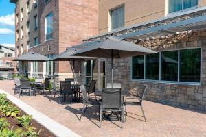 卡梅尔Fairfield Inn & Suites by Marriott Indianapolis Carmel的大楼前方设有带桌椅和遮阳伞的天井。