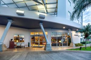 阿拉胡埃拉阿拉胡埃拉圣荷西机场万怡酒店的一座带玻璃门和棕榈树的建筑