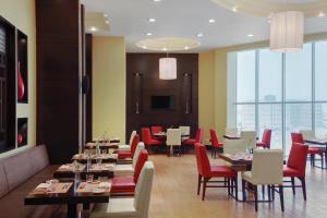 吉赞吉赞万怡酒店的用餐室配有桌子和红色椅子