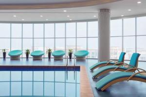 吉赞吉赞万怡酒店的大型客房带窗户,设有一座带蓝色椅子的游泳池