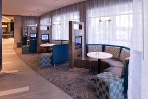 萨斯卡通萨斯卡通机场万怡酒店的一间配有沙发、桌子和窗户的等候室