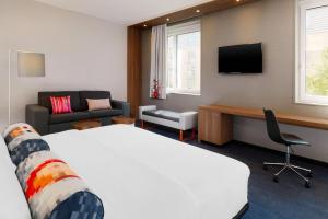 慕尼黑慕尼黑雅乐轩酒店的酒店客房设有一张床、一张书桌和一台电视机。