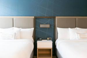 南本德SpringHill Suites by Marriott South Bend Notre Dame Area的两间位于酒店客房的床,中间设有一张桌子