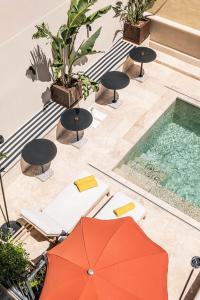 纳博讷Hôtel Le Mosaïque的享有带橙色遮阳伞的游泳池的顶部景致