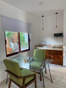 锡瓦塔塔内霍Luana Suites- Suite Maya的厨房配有玻璃桌和两把绿色椅子
