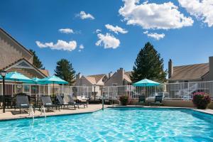 博尔德Residence Inn by Marriott Boulder的一个带椅子和遮阳伞的游泳池