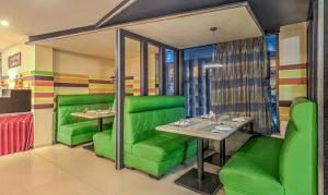 海得拉巴Treebo Tryst Metropolis的一间餐厅,房间内设有绿色的椅子和桌子