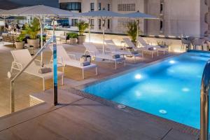 圣克鲁斯-德特内里费AC Hotel by Marriott Tenerife的一座带椅子和遮阳伞的游泳池位于一座建筑旁边