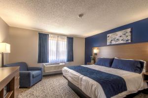 GroveHilltop Inn & Suites的配有一张床和一把椅子的酒店客房