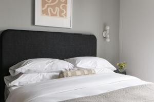 伯明翰Mint House Birmingham - Downtown的一张带黑色床头板和白色枕头的白色床