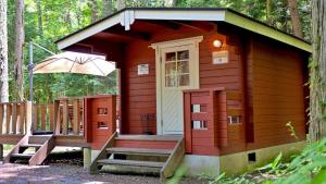 富士河口湖Work Shop Camp Resort Forest and Lake Paradise - Vacation STAY 85274v的一间红色的小小屋,设有门廊和雨伞