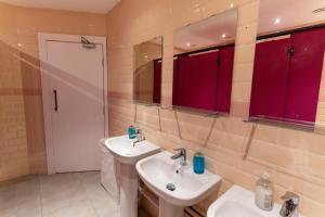 伦敦Hostelle - women only hostel London的一间带两个盥洗盆和红色橱柜的浴室