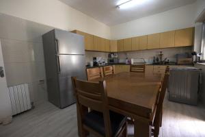 拉马拉Ramallah Hostel的厨房配有木桌和不锈钢冰箱。