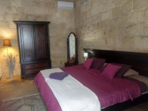 拉巴特Villa Vittoria的一间卧室配有一张带紫色枕头的大床