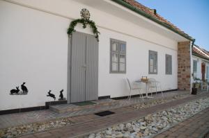 AgyagosszergényNótás Tücsök Vendégház的白色的房子,有门和桌子