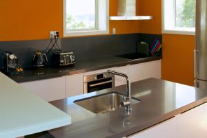 福克斯冰川福克斯教堂度假屋的厨房设有不锈钢水槽和橙色墙壁