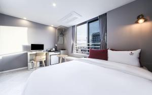 釜山Maron Hotel Nampo的卧室配有一张白色大床和一张书桌