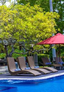 蒂瑟默哈拉默Chaarya Resort & Spa的一组椅子和一把遮阳伞,位于游泳池旁