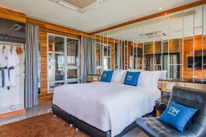普吉镇NH Boat Lagoon Phuket Resort的卧室配有一张白色大床和一把椅子