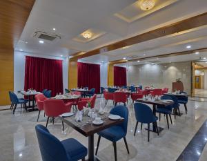 蒂鲁帕蒂Golden Tulip Tirupati的一间带桌椅和红色窗帘的餐厅