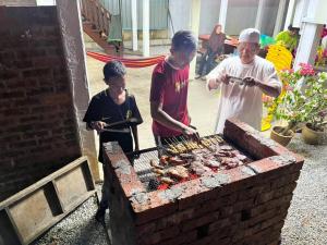 瓜拉丁加奴Inap Nekmi Kuala Terengganu With Pool的烤架上做饭的男人和两个男孩