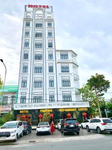 Bạc LiêuPhụng Hoàng Vũ的一座白色的大建筑,前面有汽车停放