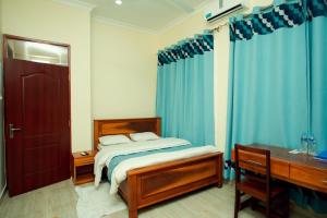 坦噶La Casa Preciosa的一间卧室配有一张床、一张书桌和蓝色窗帘