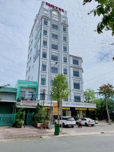 Bạc LiêuPhụng Hoàng Vũ的一座高大的白色建筑,前面有汽车停放