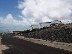 Rodrigues IslandÔ Bercail du Sud chez Jeannette的一条有房子的道路旁的石墙