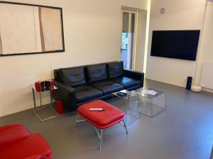 佩萨罗luxury apartment的客厅配有黑色真皮沙发和红色凳子