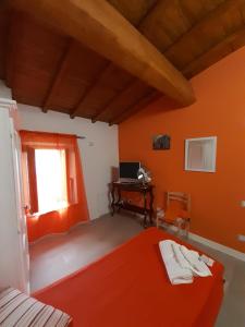 博马尔佐B&B Il Grifo的一间卧室设有橙色的墙壁、一张床和一张书桌
