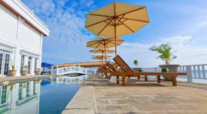 吉利特拉旺安Gili Beachfront Suites的大楼旁的带长椅和遮阳伞的游泳池
