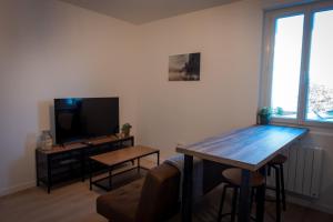 勒芒Bonuit的客厅配有桌子和电视