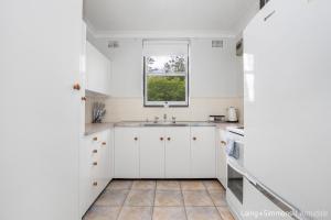 阿米代尔TC GARDENS 11的白色的厨房设有水槽和窗户