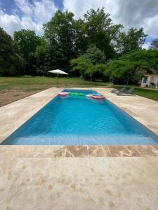贝尔热拉克la Chartreuse du Domaine de la Graulet的院子里一个空的游泳池,上面有雨伞