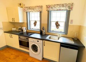 柯克纽顿Pentland Farm Cottage Annex的厨房配有水槽和洗衣机