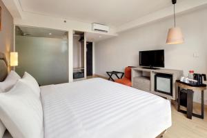 勒吉安Harper Kuta Hotel by ASTON的卧室配有一张白色大床和电视。