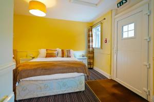 里彭OYO The White Horse, Ripon North Yorkshire的一间卧室设有一张床和黄色的墙壁