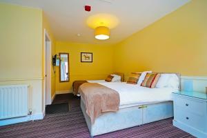 里彭OYO The White Horse, Ripon North Yorkshire的一间卧室设有两张床和黄色的墙壁