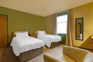 里彭OYO The White Horse, Ripon North Yorkshire的酒店客房,设有两张床和一张沙发