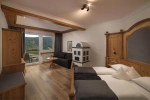 布鲁尼科Schönblick - Sport & Active Hotel的一间卧室配有一张床、一张沙发和一个窗口